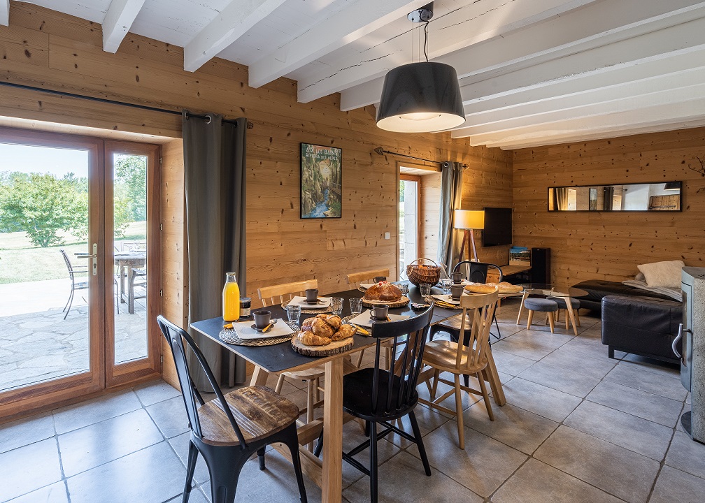 Une jolie table dressée avec des croissants, un joli panier, une brioche, du jus de pomme, de la confiture locale