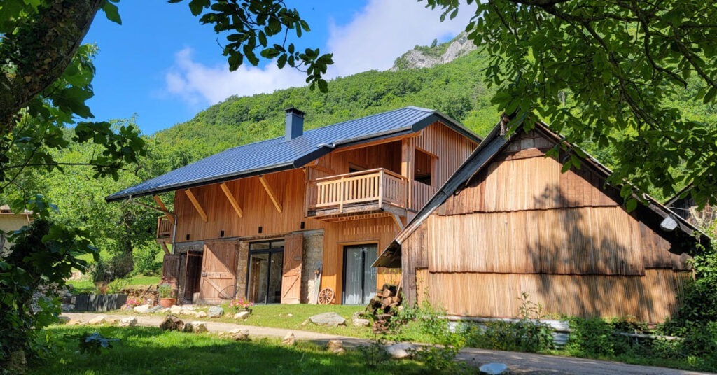 L'Alpage, vue dans son ensemble depuis le jardin. Une ancienne grange rénovée en pierres et en bois.