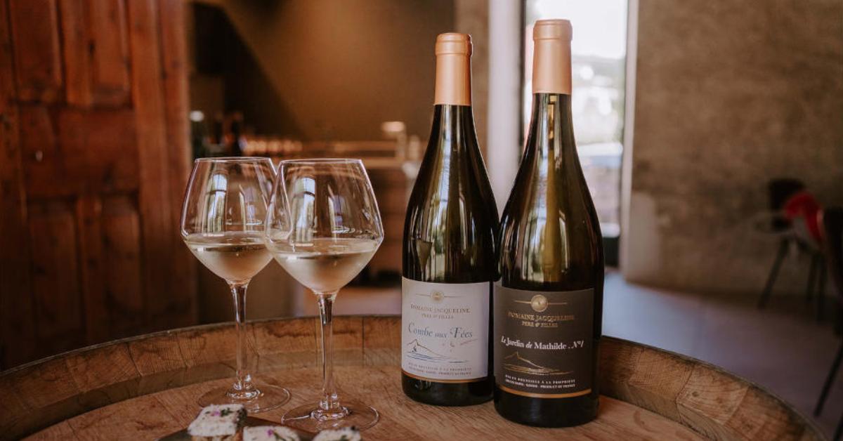 Deux bouteilles et deux verres de vin sont dressés sur une petite table ronde.
