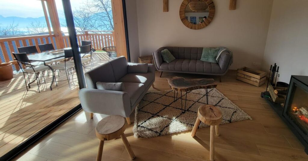 Le salon du gîte de l'Eterlou à L'Alpage avec ses deux canapés, son poêle  à bois et ses larges baies vitrées. 