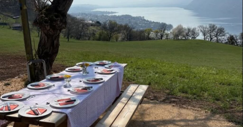 Une table est dréssée pour 10 personnes, face au Lac du Bourget et en pleine nature, dans le jardin de L'Alpage.