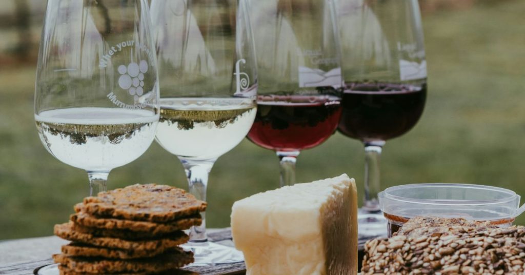 Un table avec 2 verres de vin banc et 2 verres de vin rouge et quelques spécialités locale sà déguster, dans le cadre d'un atelier d'oenologie pour un séminaire d'entreprise à L'Alpage.