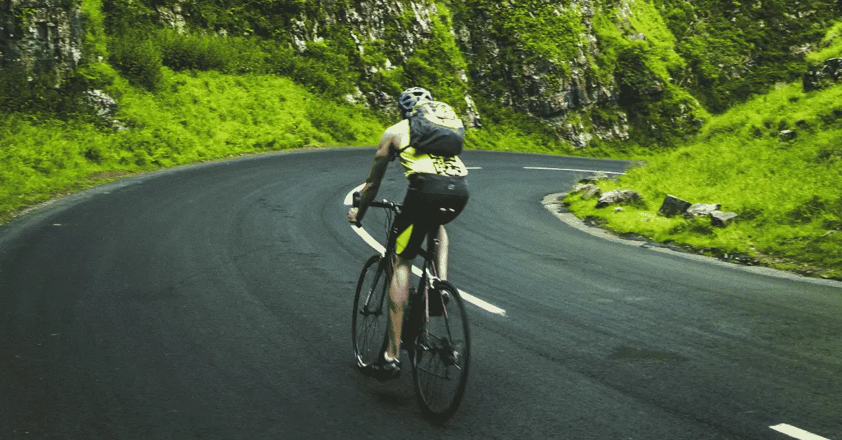 cyclisme-savoie-haute-savoie-bauges-gites-les-granges-de-capucine Un cycliste roule de dos, en descente, sur une route de montagne, en Savoie, proche des gites Les Granges de Capucine