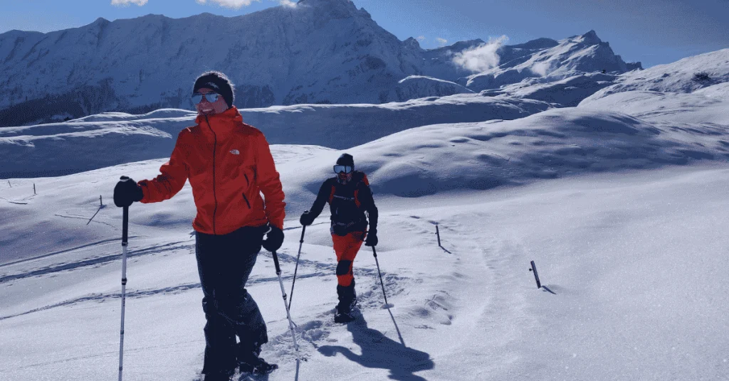 randonnee-raquettes-neige-savoie-haute-savoie-bauges-gites-les-granges-de-capucine Un couple randonne en raquettes à neige dans un décor de montagnes enneigées, pendant leur séjour dans les gites Les Granges de Capucine