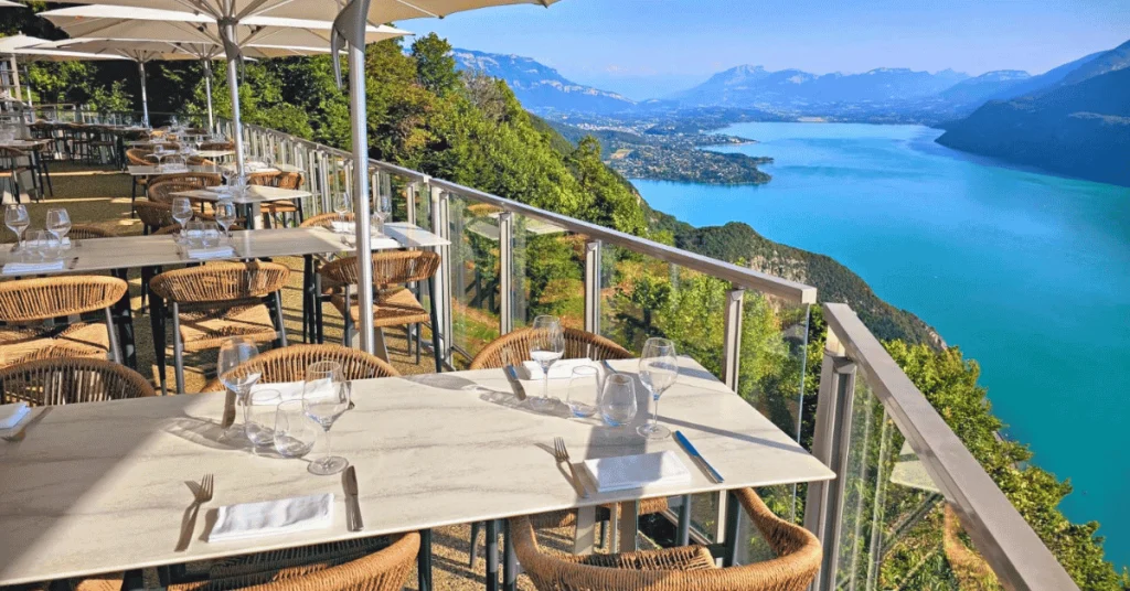 restaurant-lac-du-bourget-chambotte-alpage-gites-les-granges-de-capucine Un restaurant et ses tables dressées sur une terrasse avec une vue magnifique sur le Lac du Bourget.